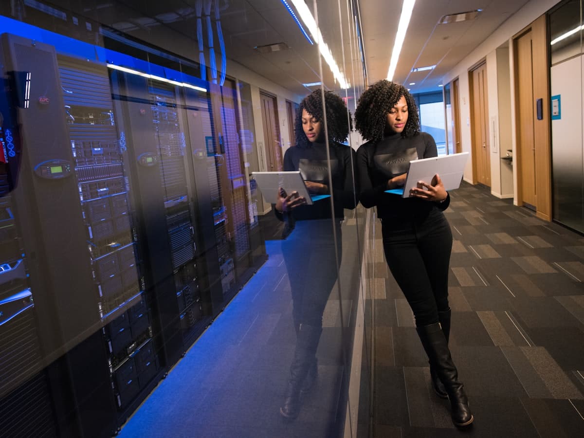 An engineer walking a lit corridor of server racks